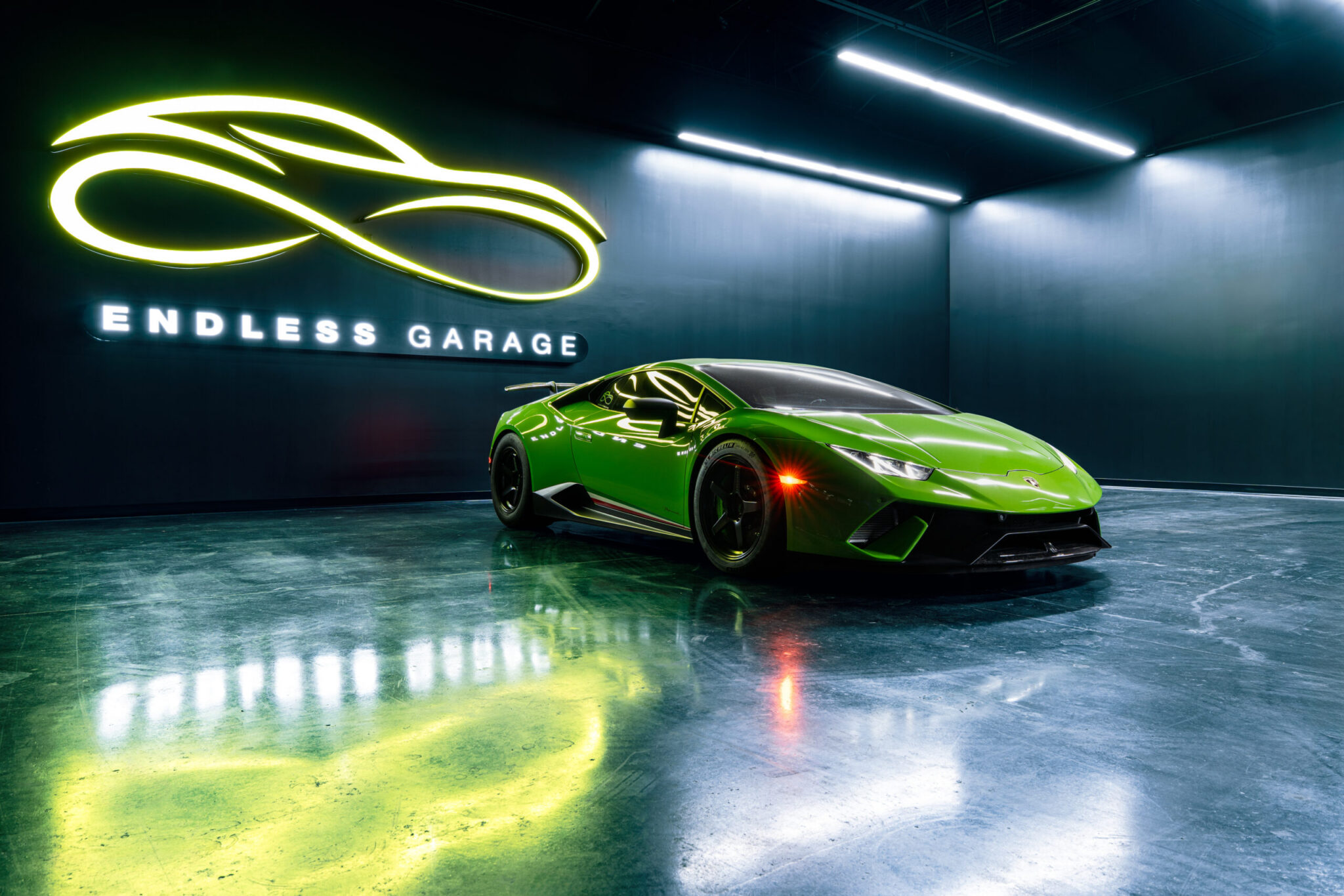 A bright green Lamborghini parked in a sleek garage with polished floors and ambient lighting. The wall features a glowing logo and the text 'ENDLESS GARAGE'.