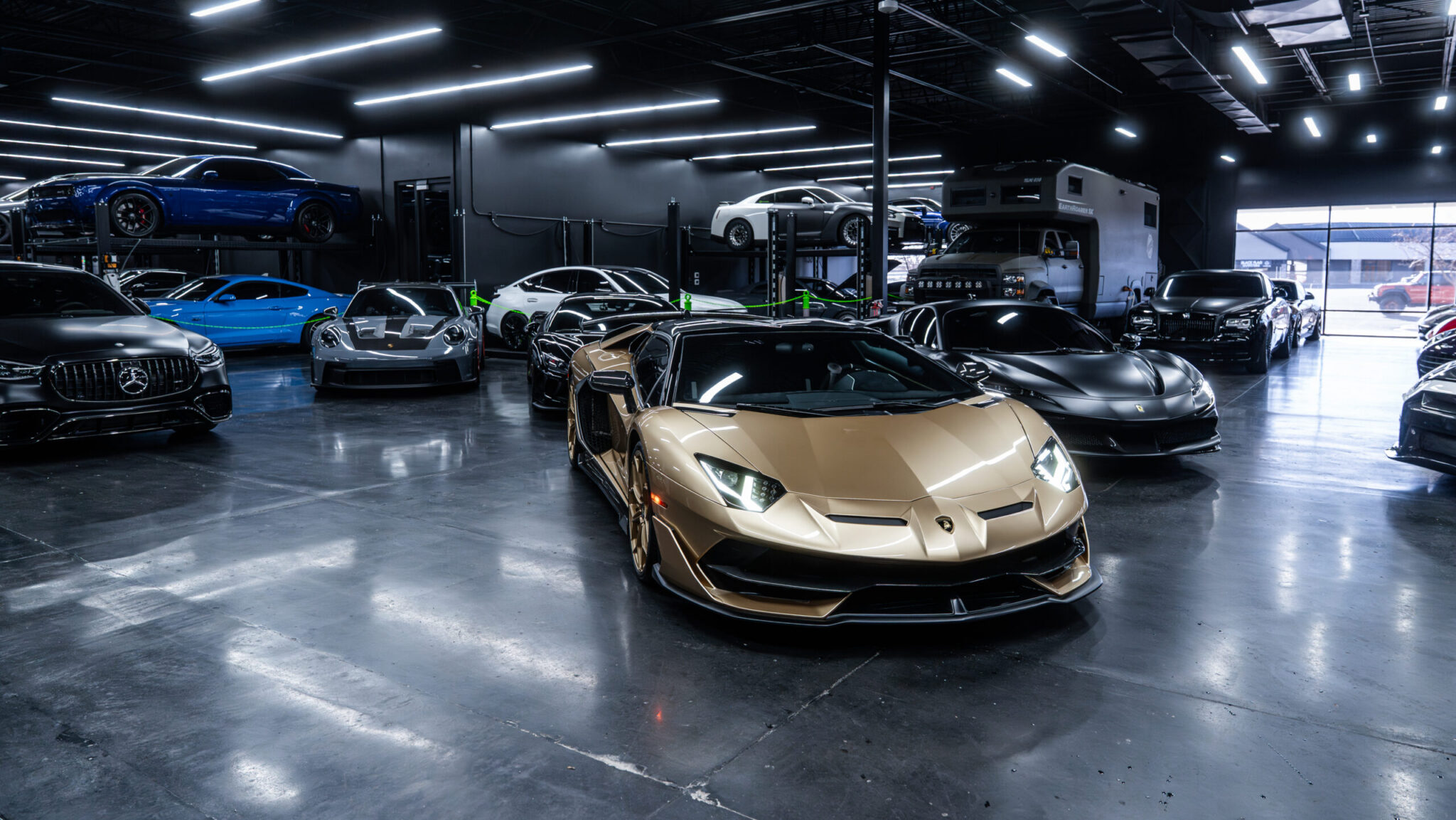 A luxurious automotive showroom featuring multiple high-performance cars including a gold Lamborghini at the forefront, surrounded by various sporty vehicles and ambient lighting.